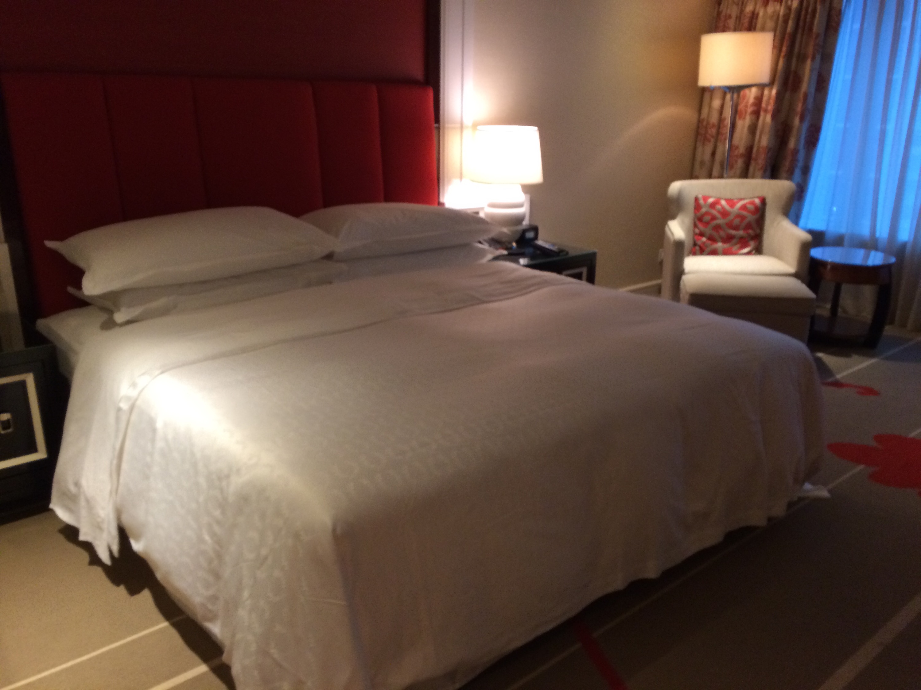 a bed with white sheets and a red headboard