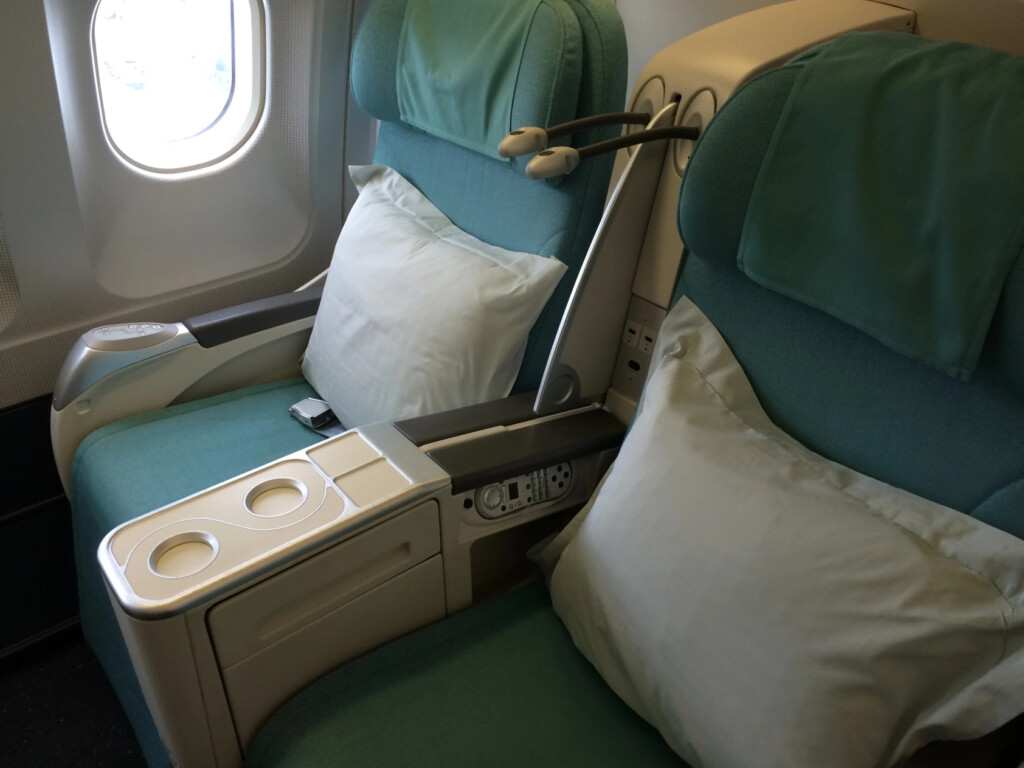 a seat with a pillow and arm rest in the middle of a plane