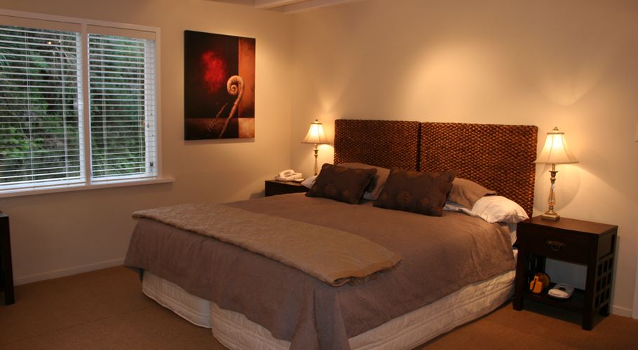 a bed with a lamp and a painting on the wall