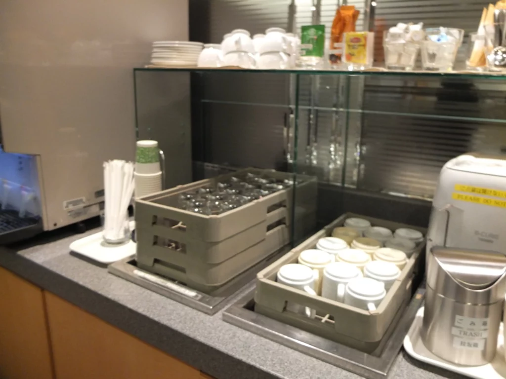 a counter with a glass case and a tray of coffee cups