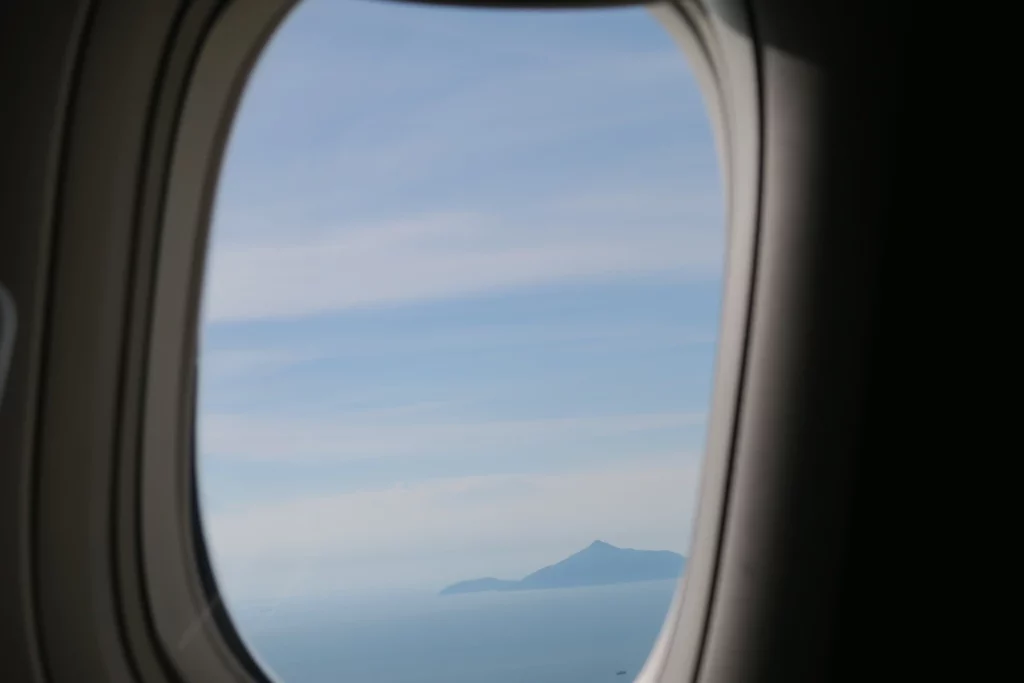 an airplane window with an island in the distance