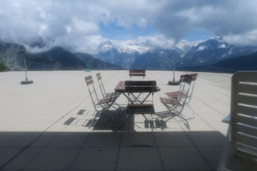 a table and chairs on a terrace with mountains in the background