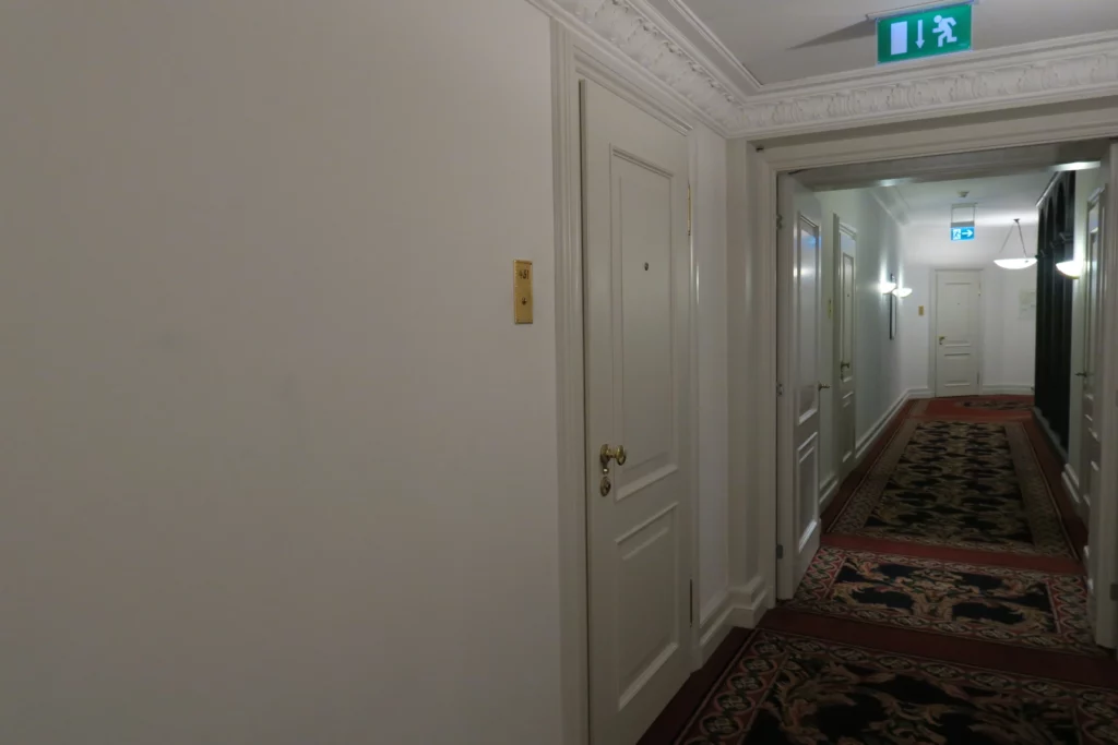 a hallway with white doors and a green sign