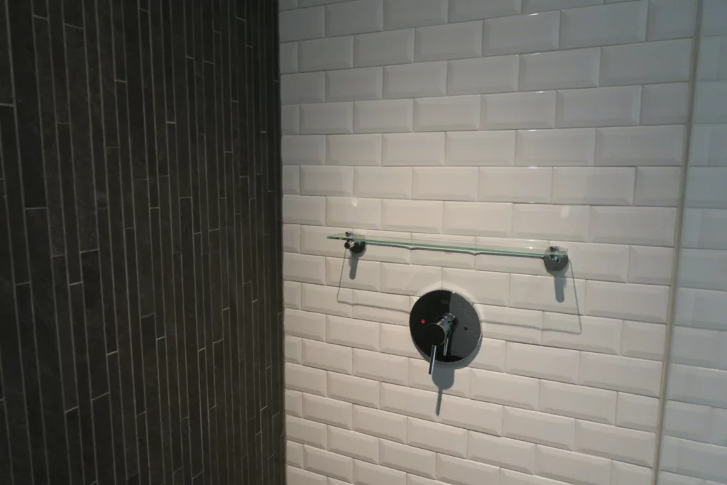 a shower with a faucet and a tile wall