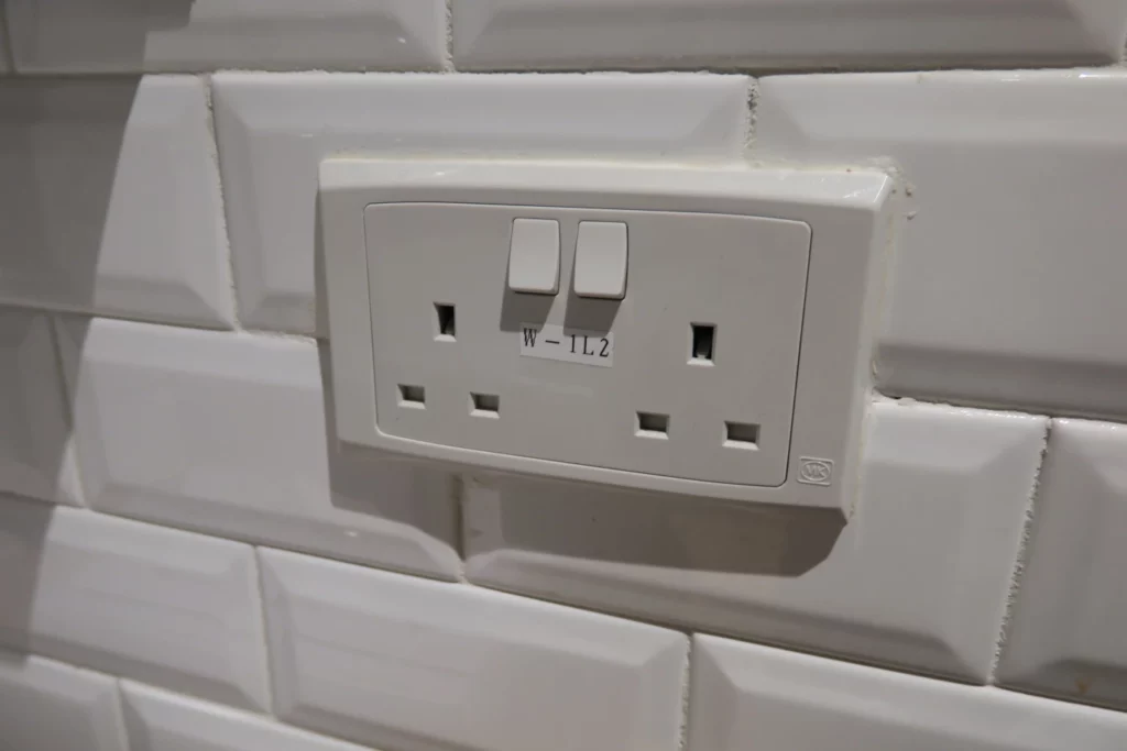 a white outlet with two switches on a white tile wall