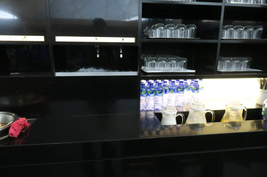 a black counter with shelves full of glasses and water