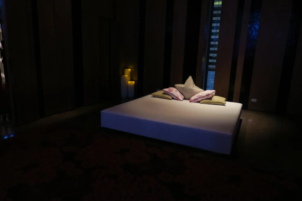 a bed with pillows and candles in a dark room