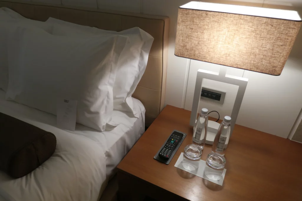 a bed with a remote control and bottles on a table
