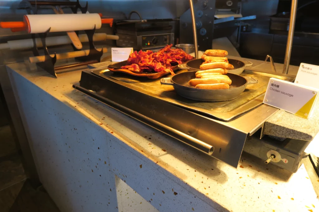 a pans of sausages and bacon on a counter