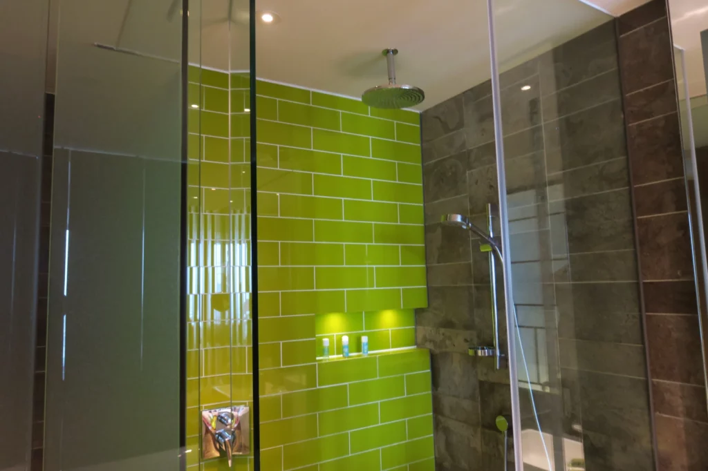 a green tile shower with a shower head