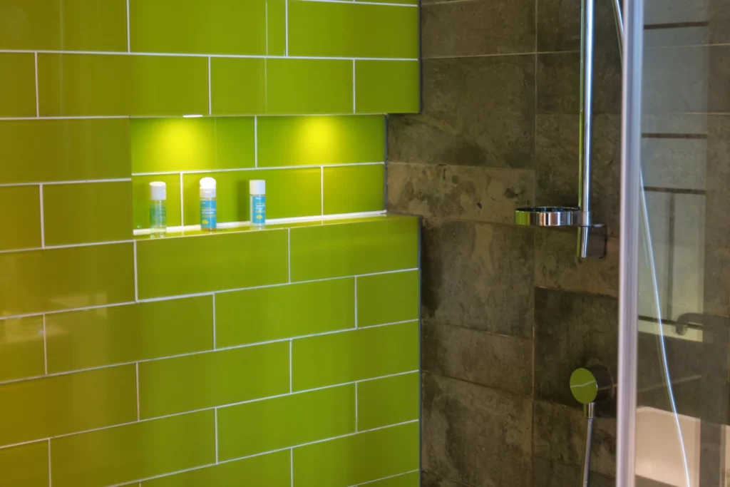 a green tile shower with white trim