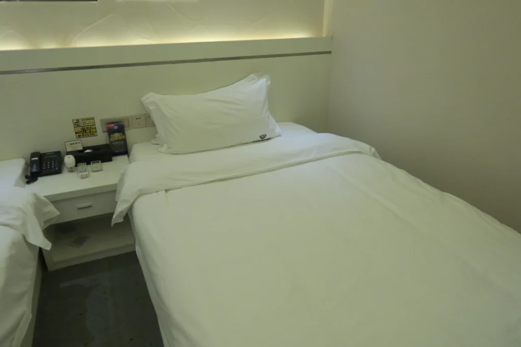 a bed with white sheets and a white pillow