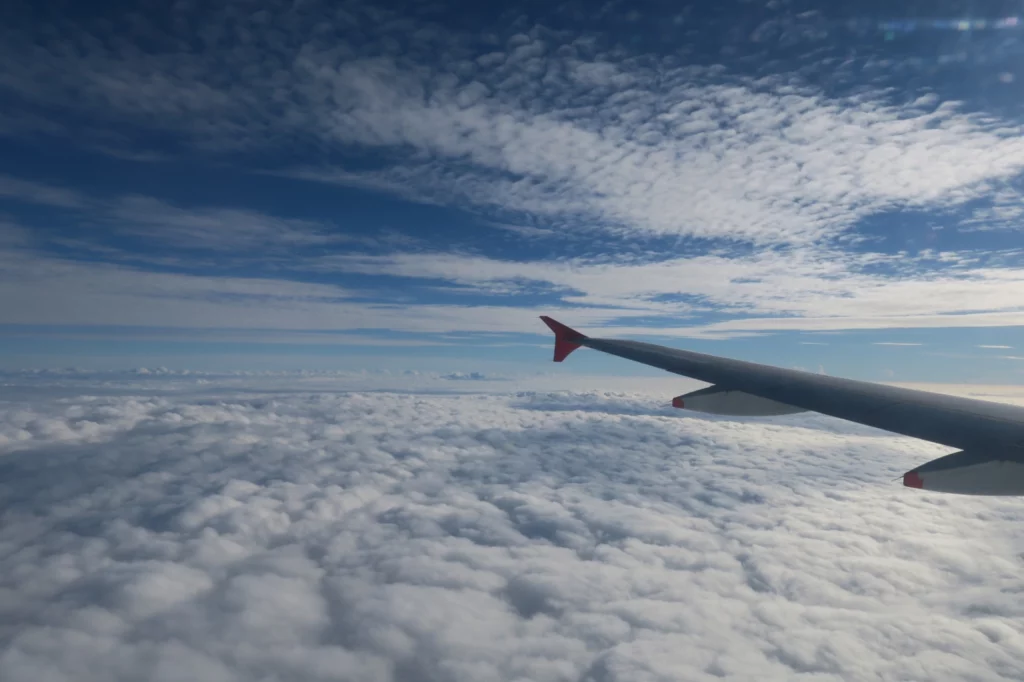 an wing of an airplane above clouds