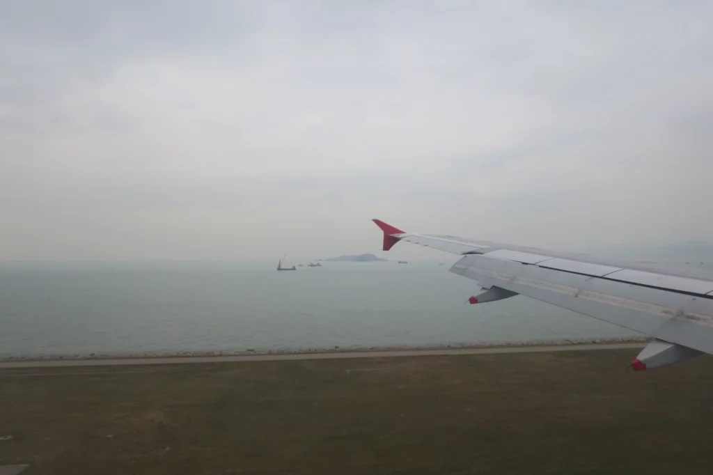 an airplane wing and land with water and land in the background