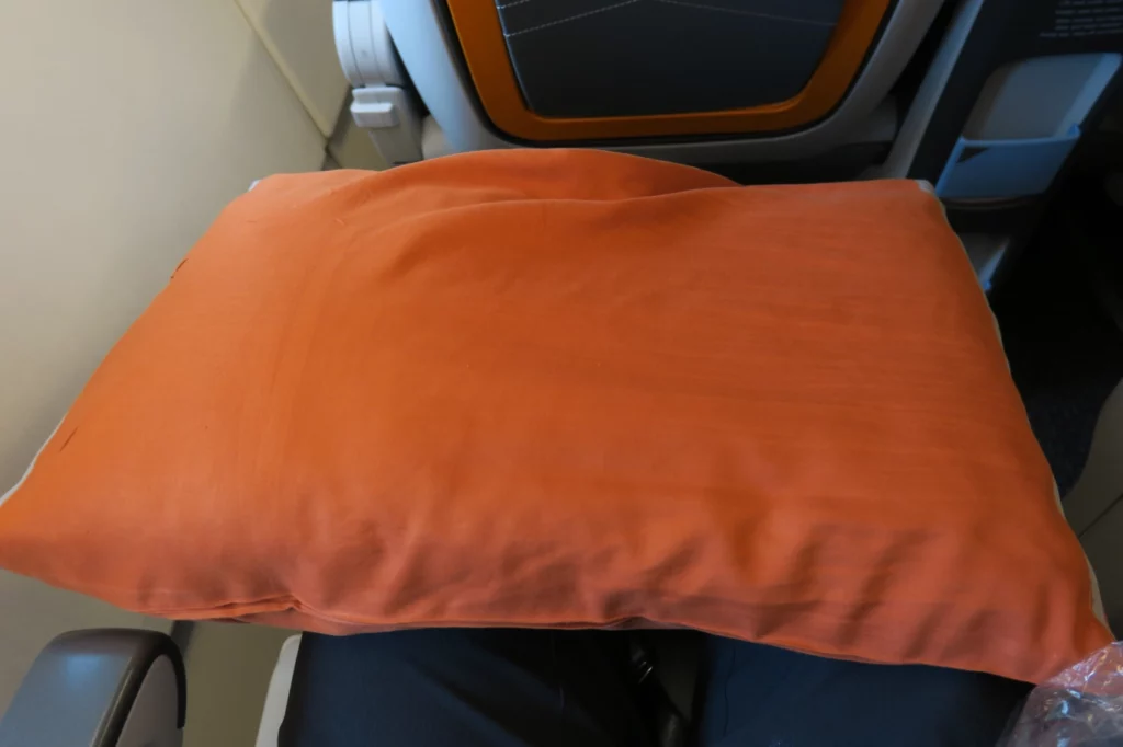 an orange pillow on a plane seat