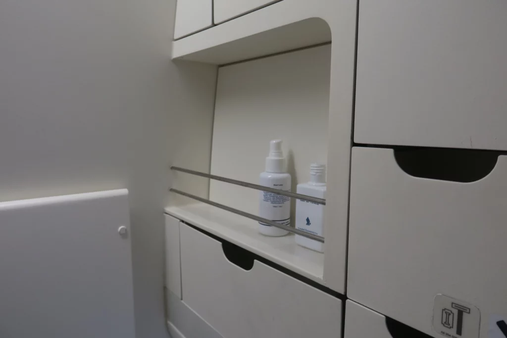 a shelf with white containers and drawers