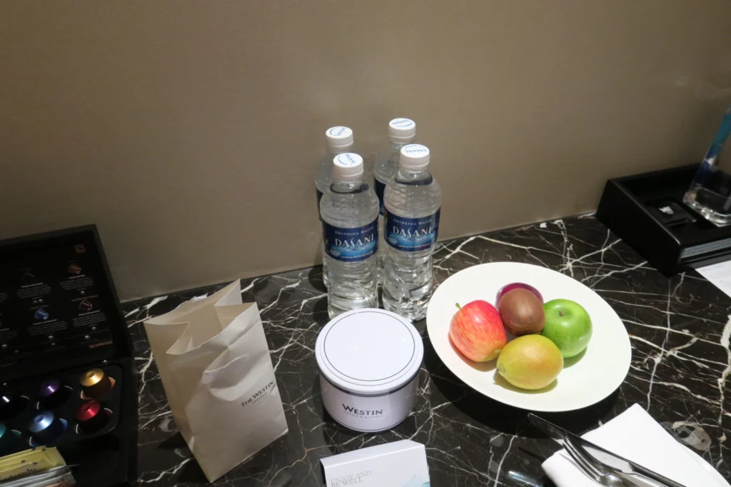 a plate of fruit and water bottles on a marble table