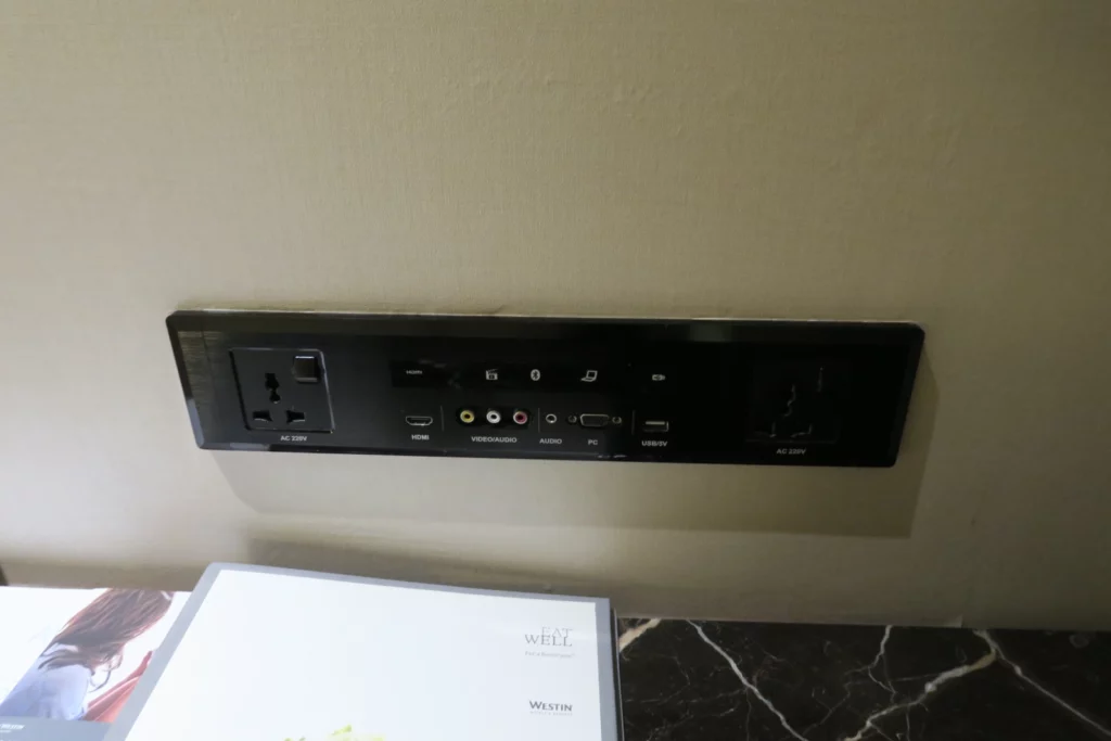 a black rectangular outlet with plugs and sockets on a wall