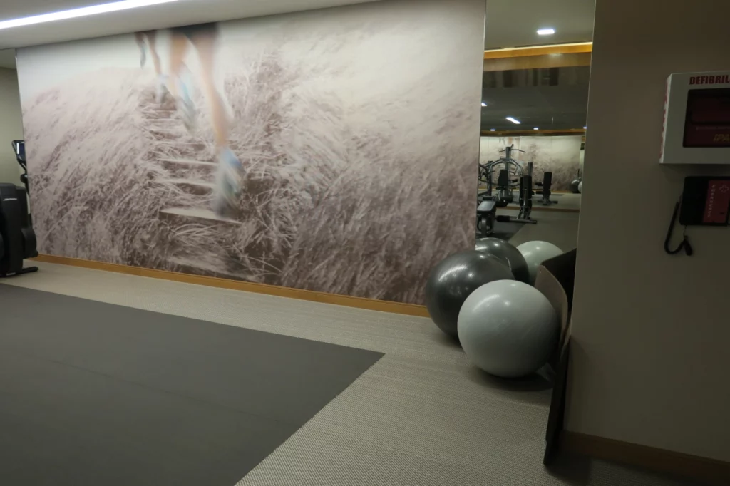 a gym with exercise equipment and a wall with a picture of a person running on the stairs