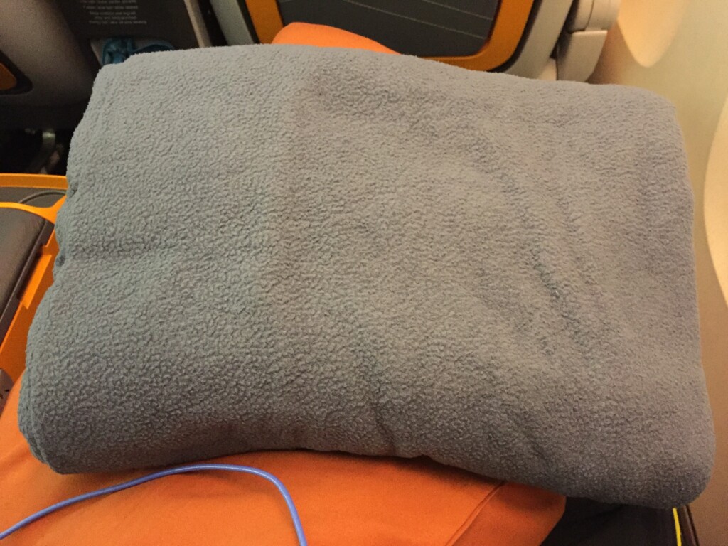 a grey blanket on an orange pillow