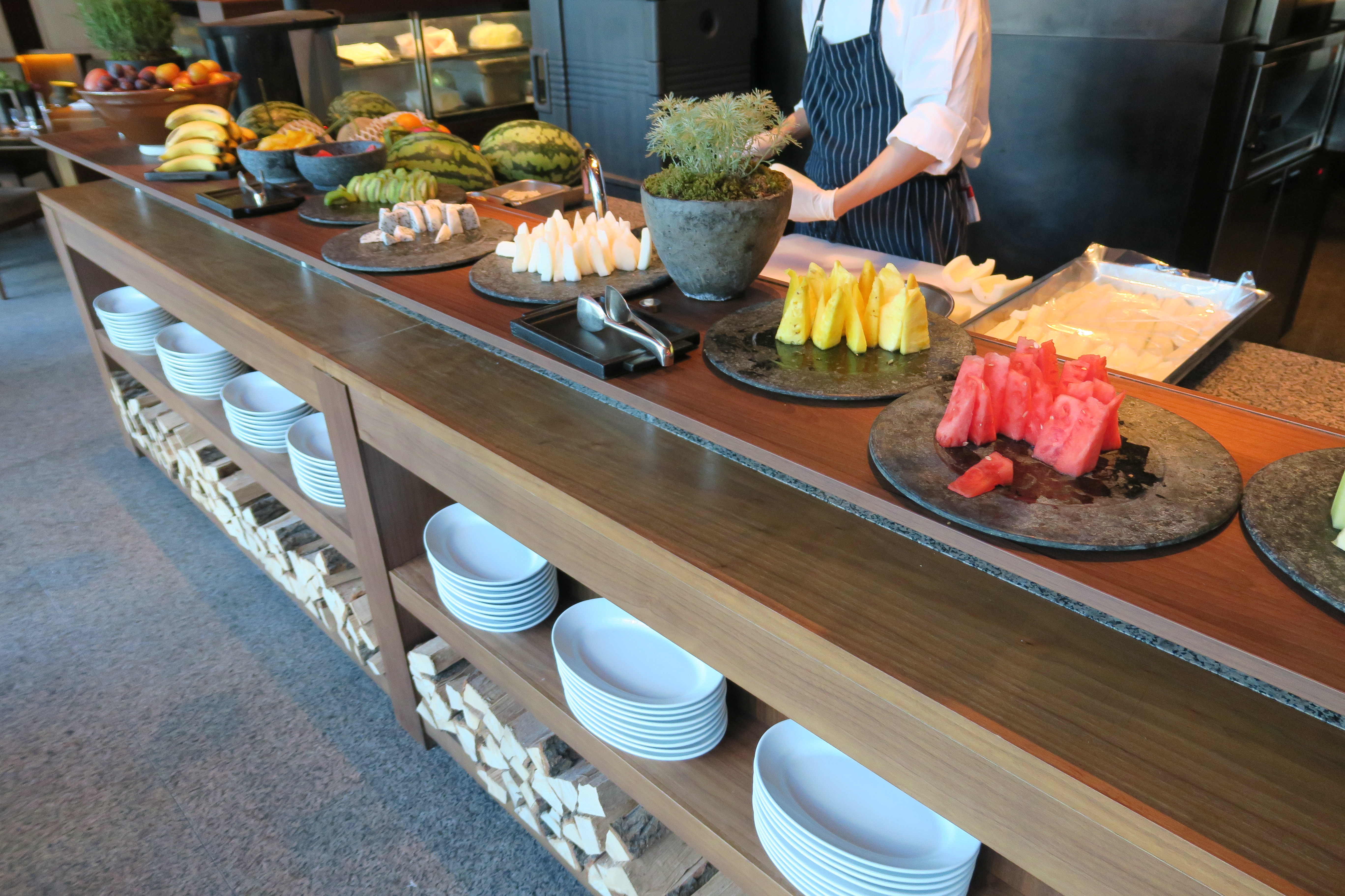 a buffet with plates of fruit and a person standing behind