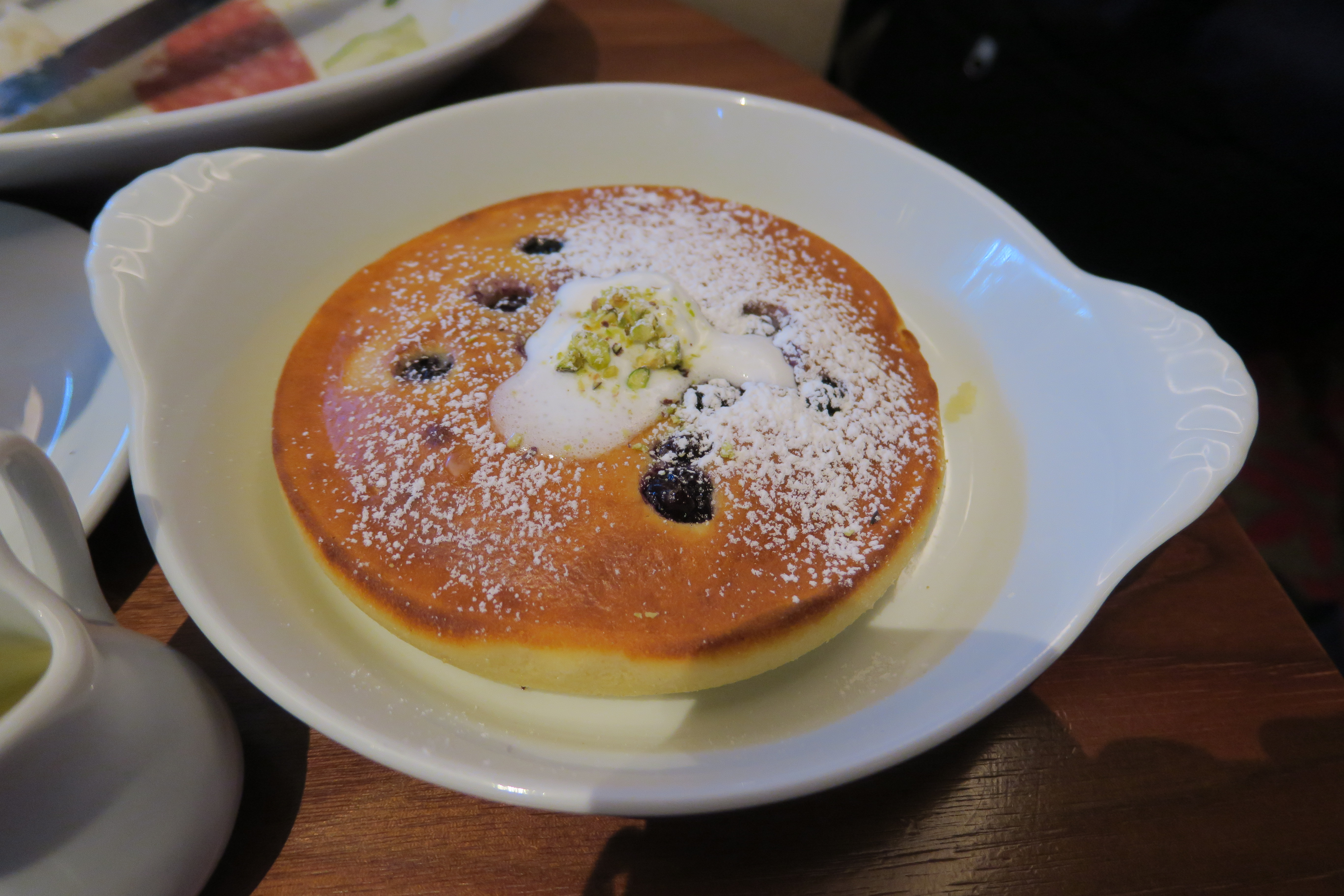 a pancake with blueberries and powdered sugar on a white plate