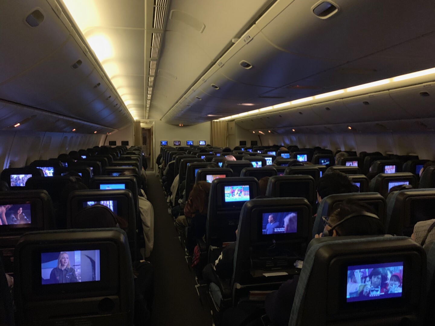 a group of people sitting in an airplane with monitors