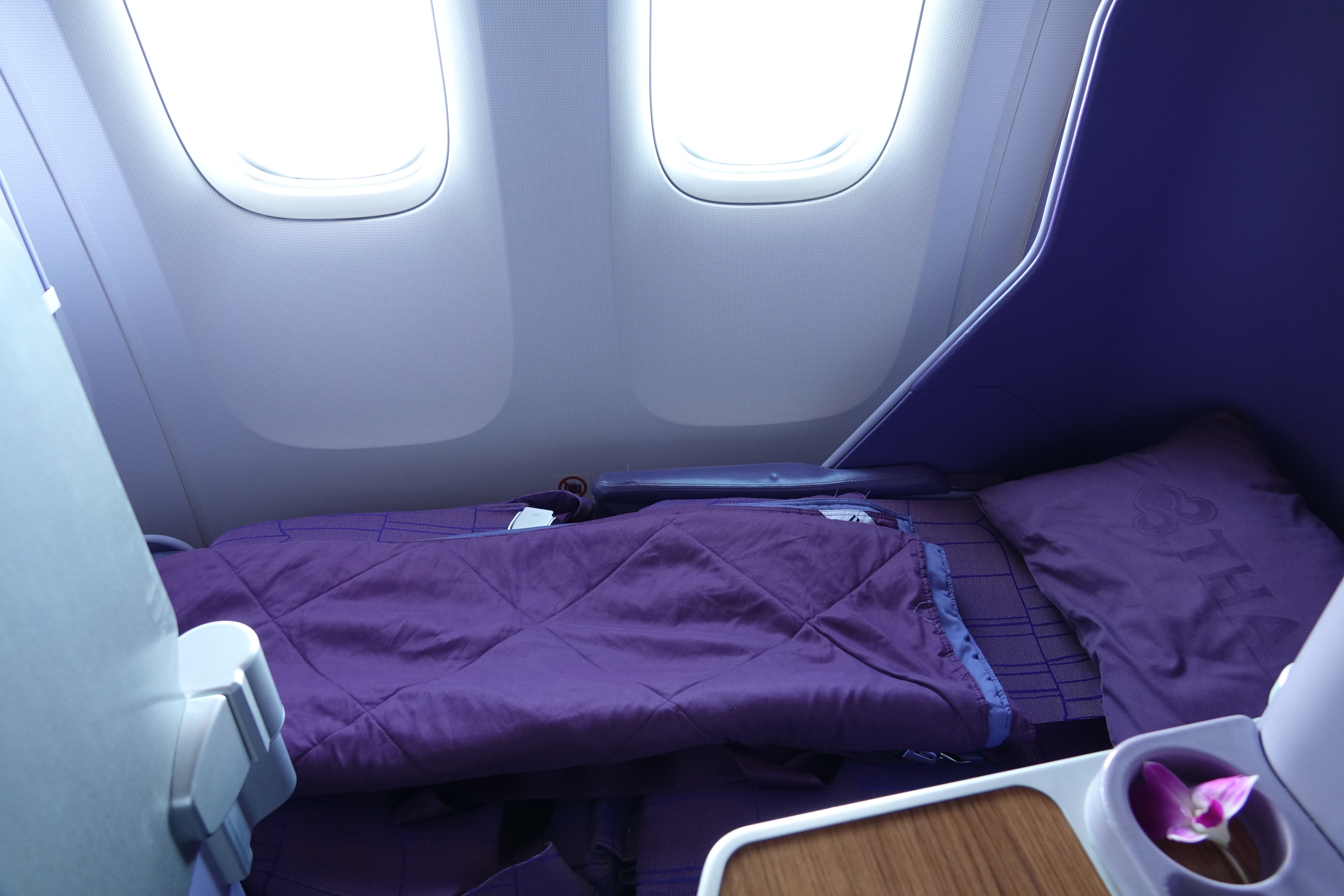 a purple blanket on a bed in an airplane