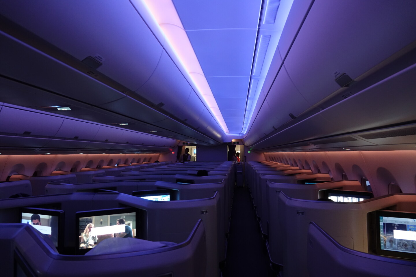 inside an airplane with rows of seats and a person standing in the back