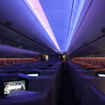 inside an airplane with rows of seats and a person standing in the back