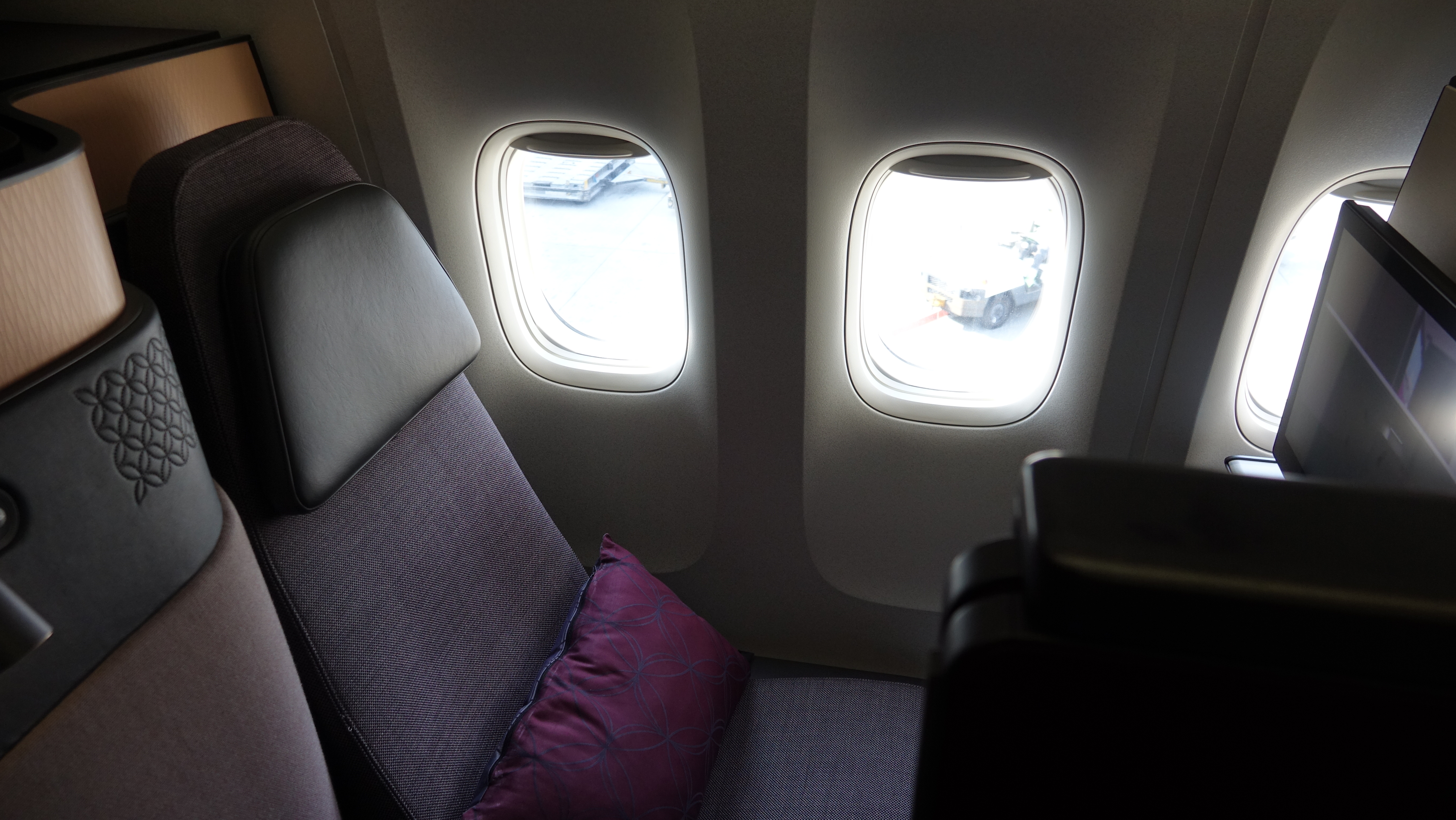 a seat with a pillow and two windows in an airplane