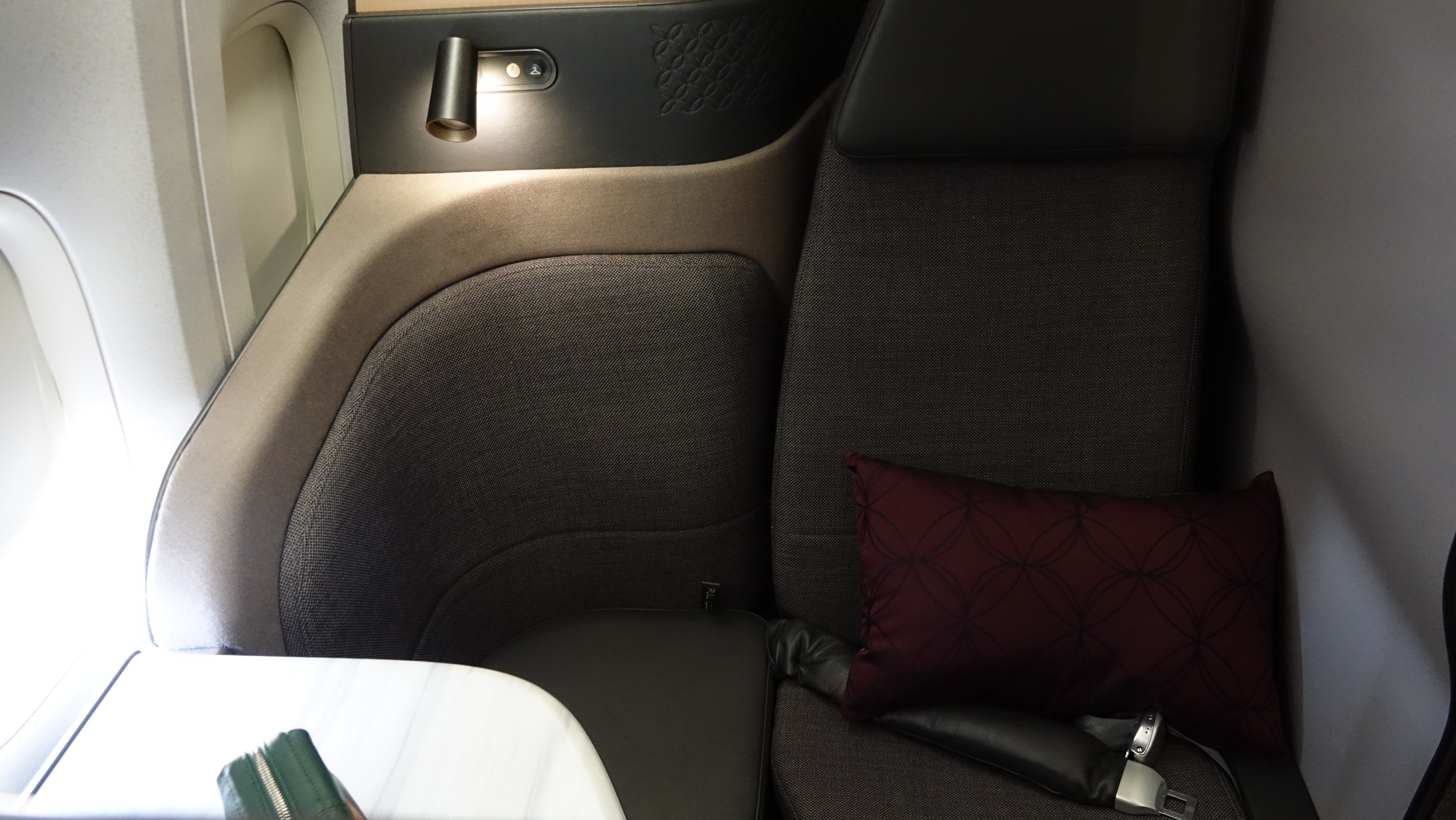 a seat with a pillow and a lamp on the side