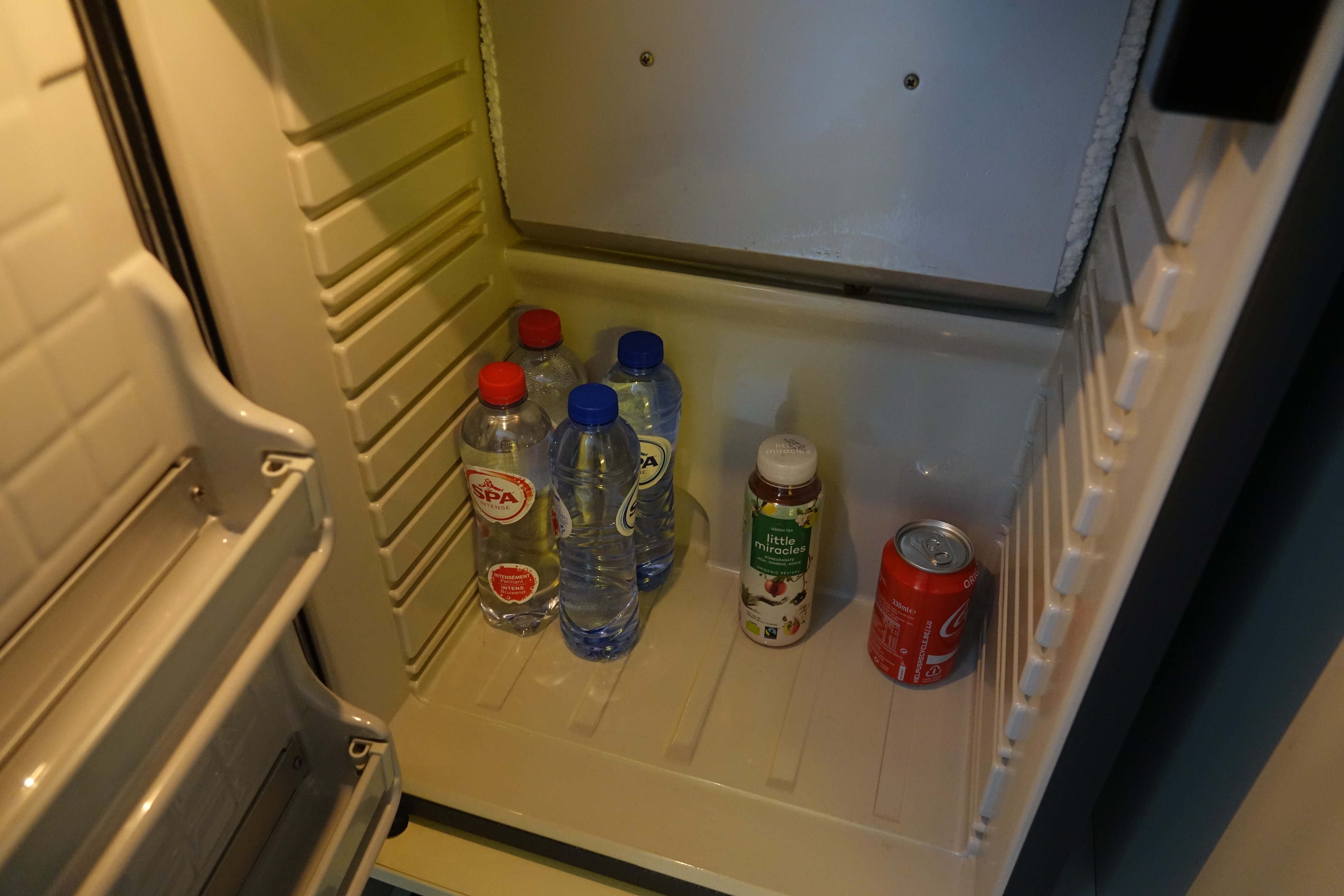 a refrigerator with bottles of soda and water