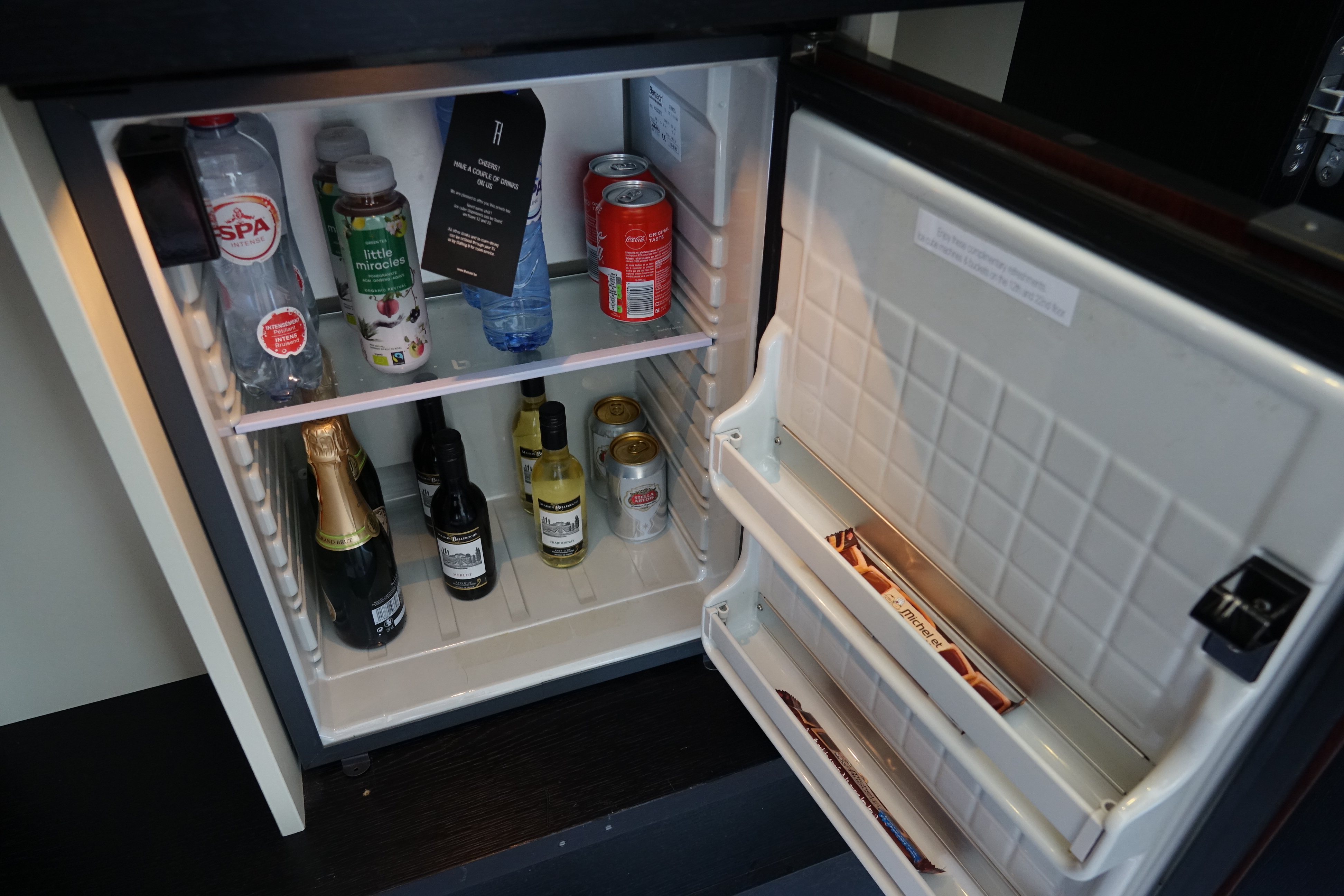 a mini fridge with bottles of alcohol and a bottle of hot water