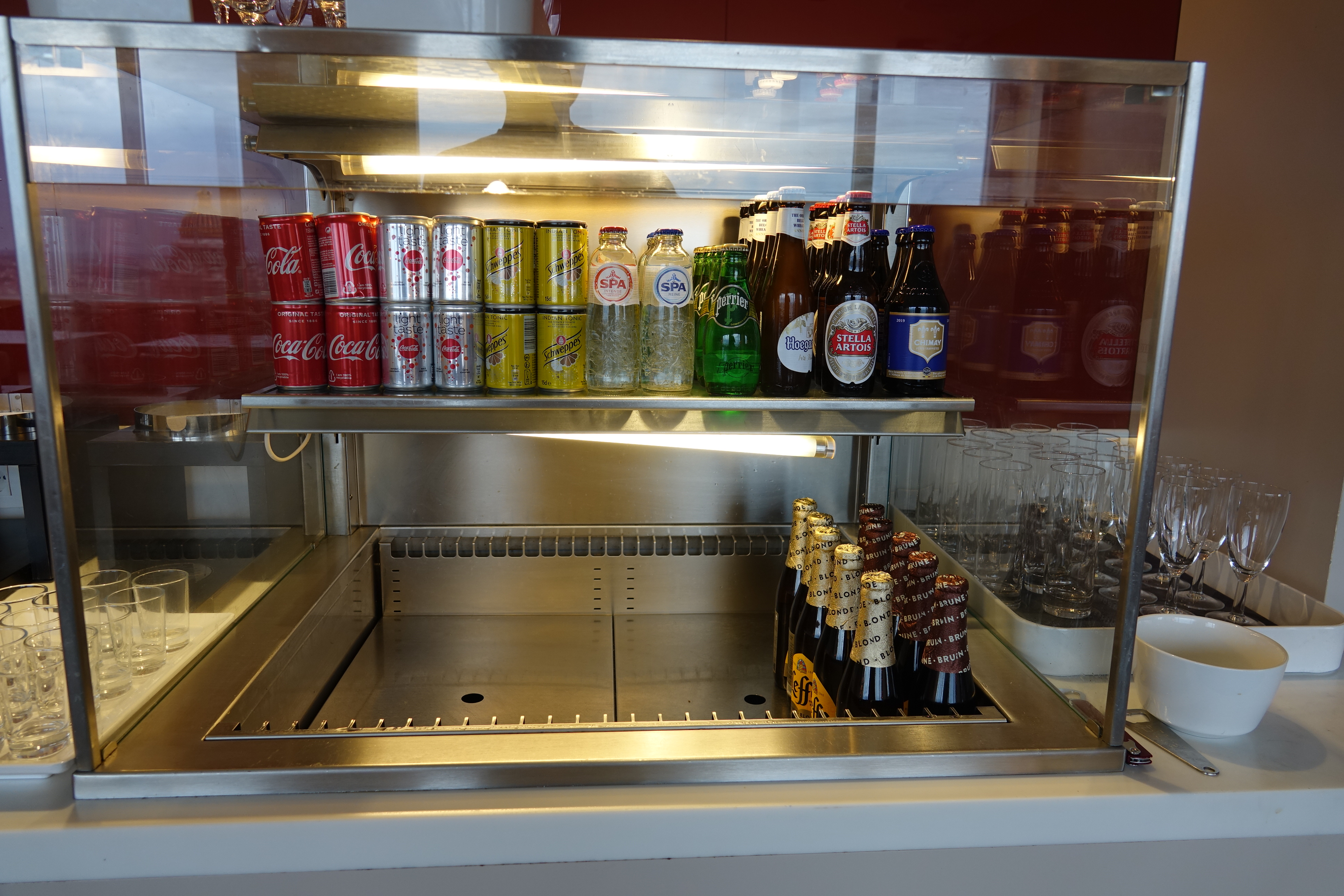 a display case with bottles of soda and glasses