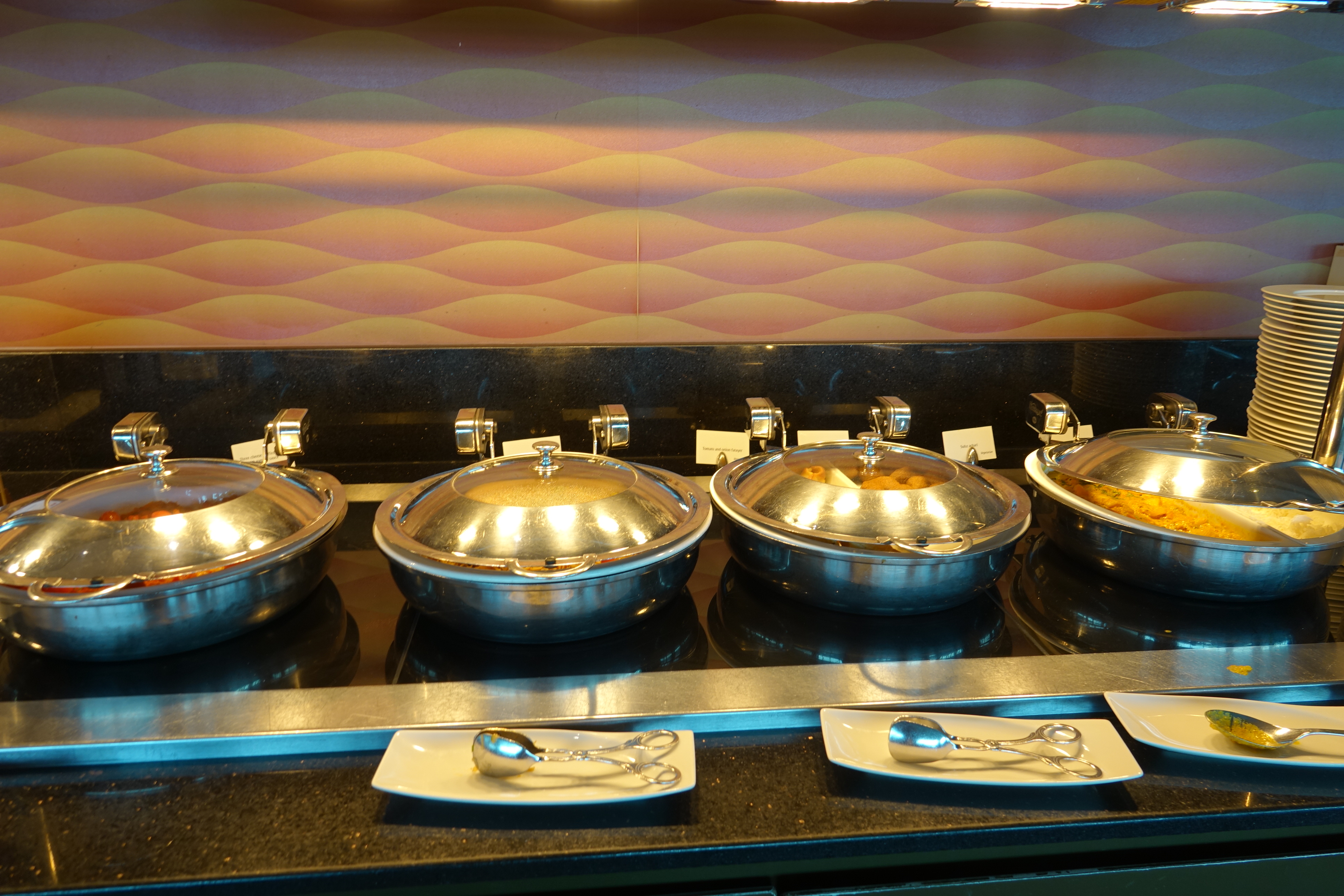 a row of silver bowls with food on a counter