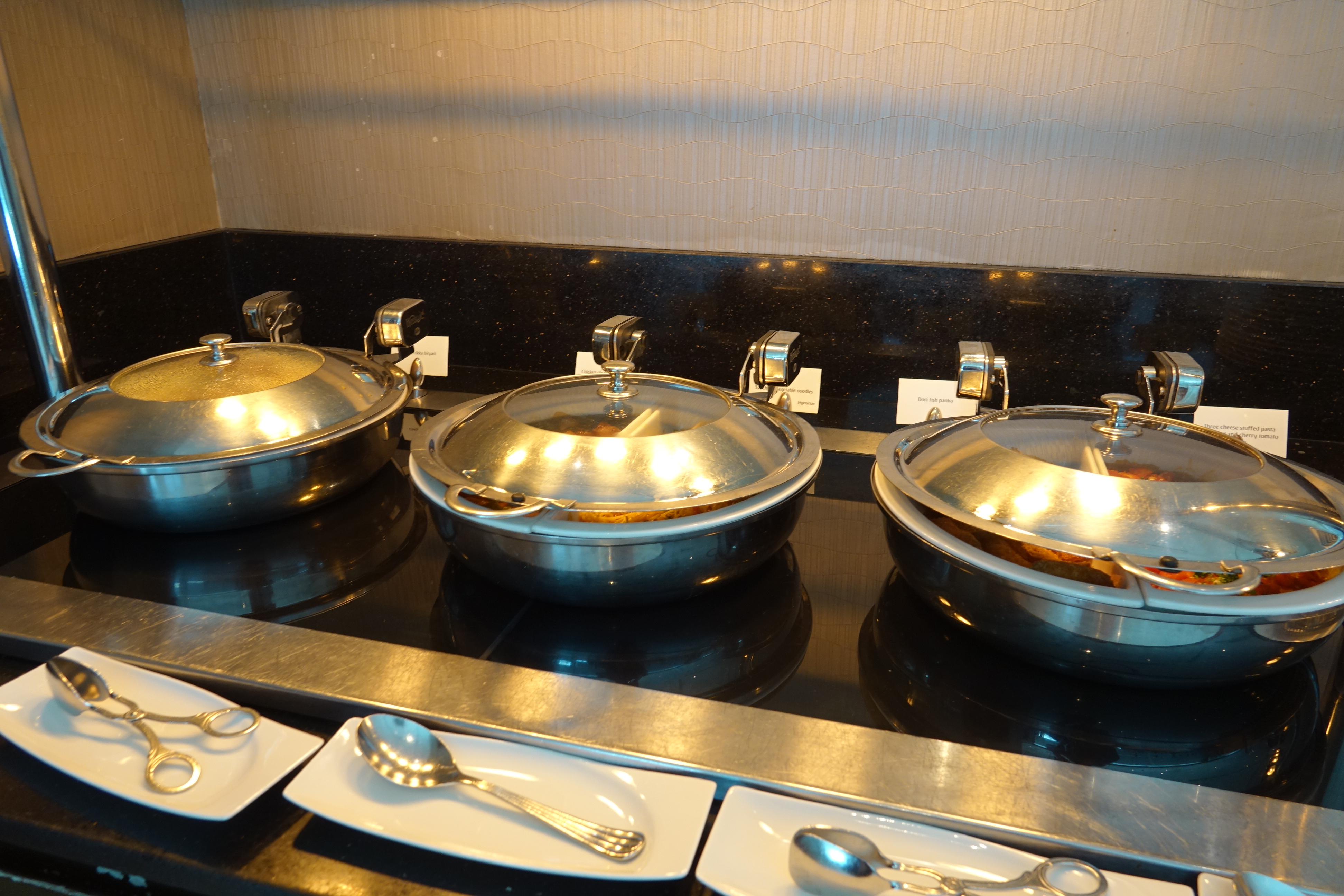 a row of silver bowls with lids on a black counter
