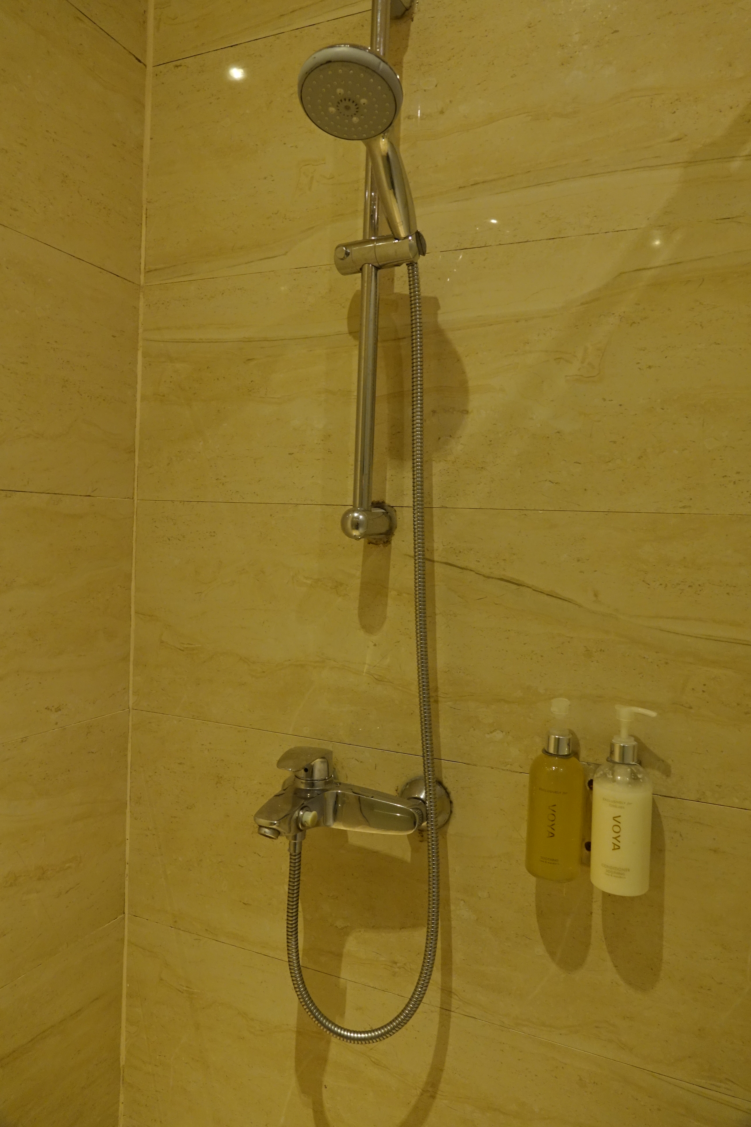 a shower head with a hose and soaps on the wall