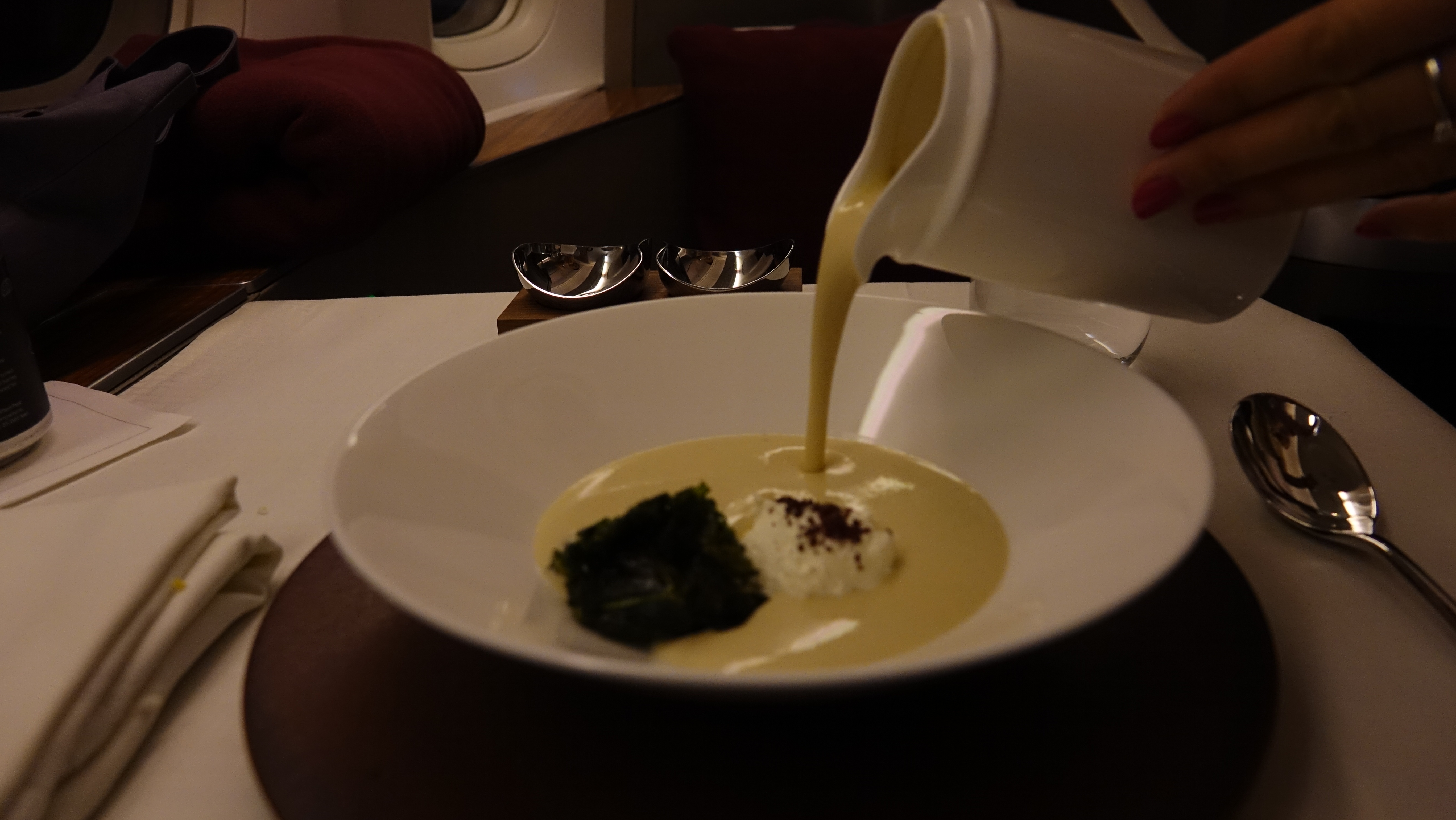 a person pouring a cream of soup into a bowl
