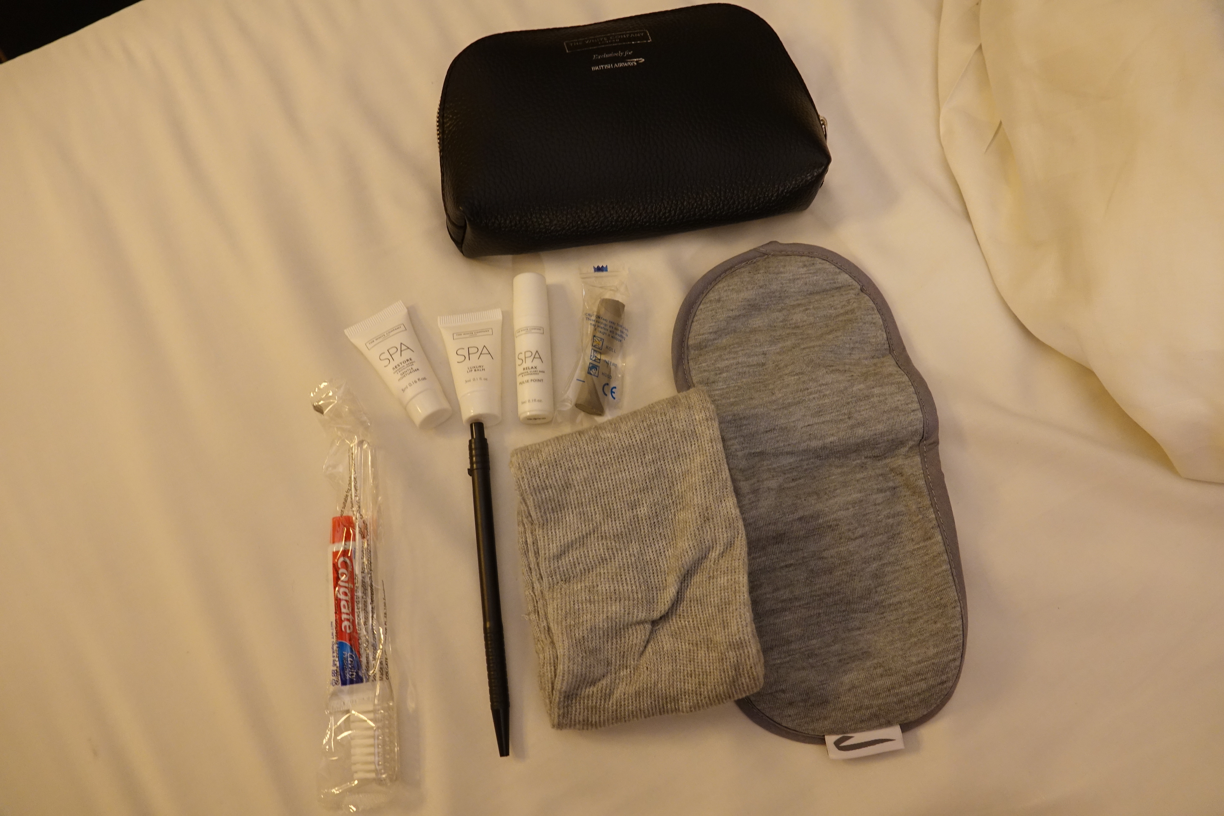 a bag with a black case and a black pen next to a black bag with toothpaste and a black object on it