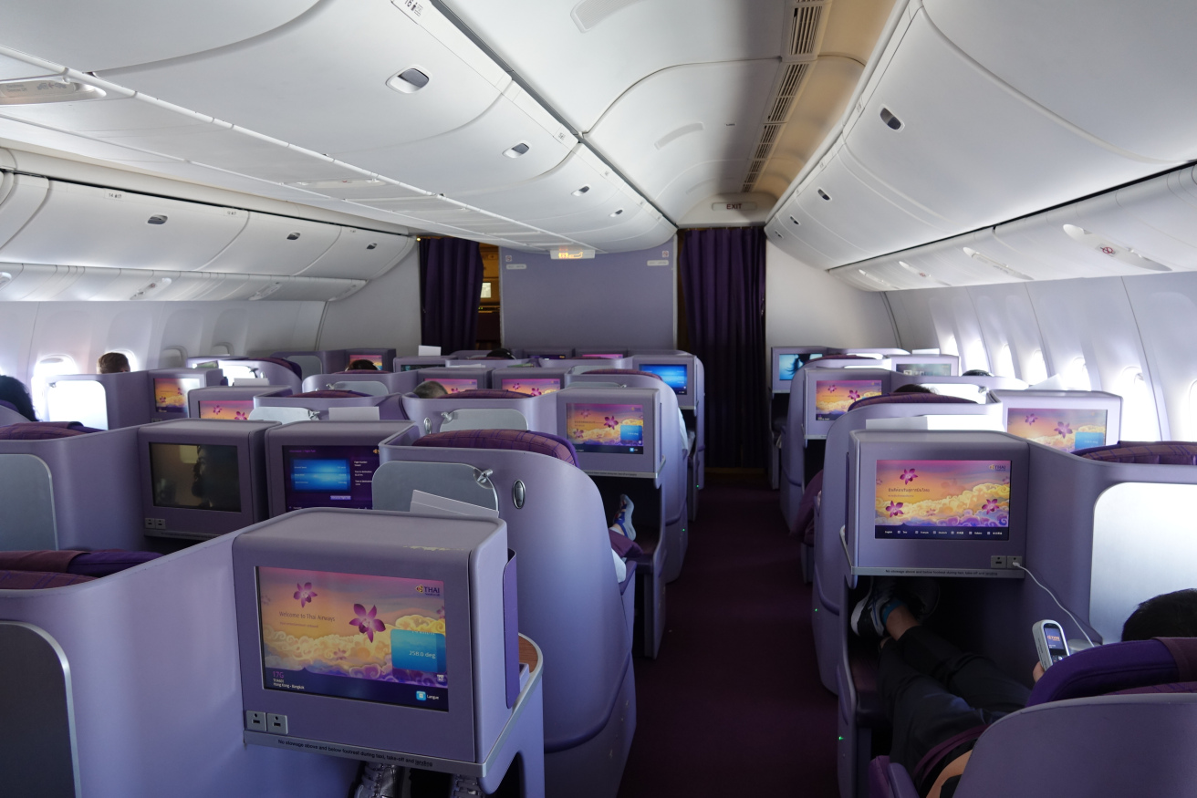 a row of seats with monitors on the back of the plane