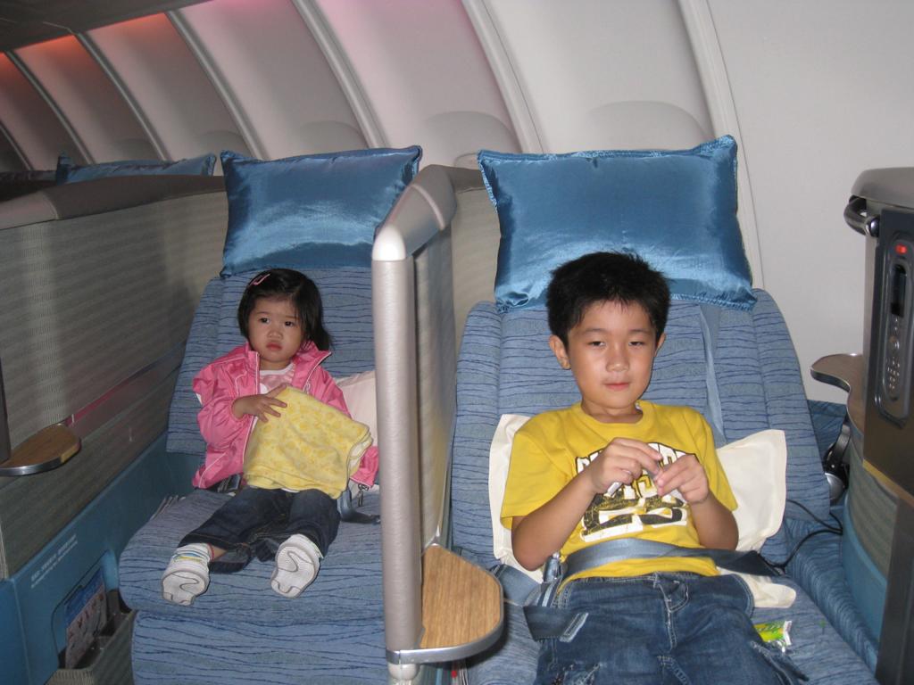 a boy and girl sitting on chairs in a plane