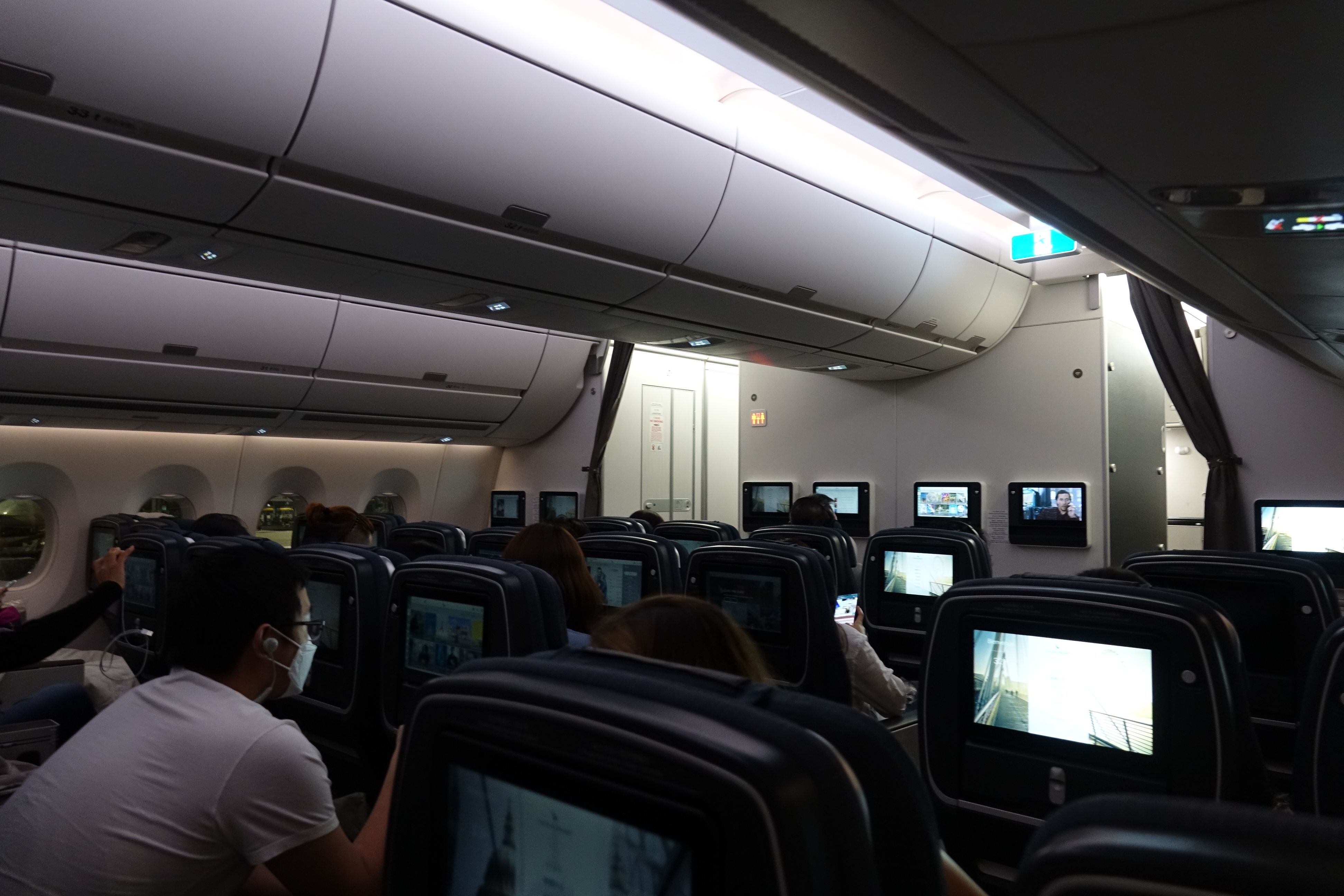 people sitting in an airplane with a group of people watching television