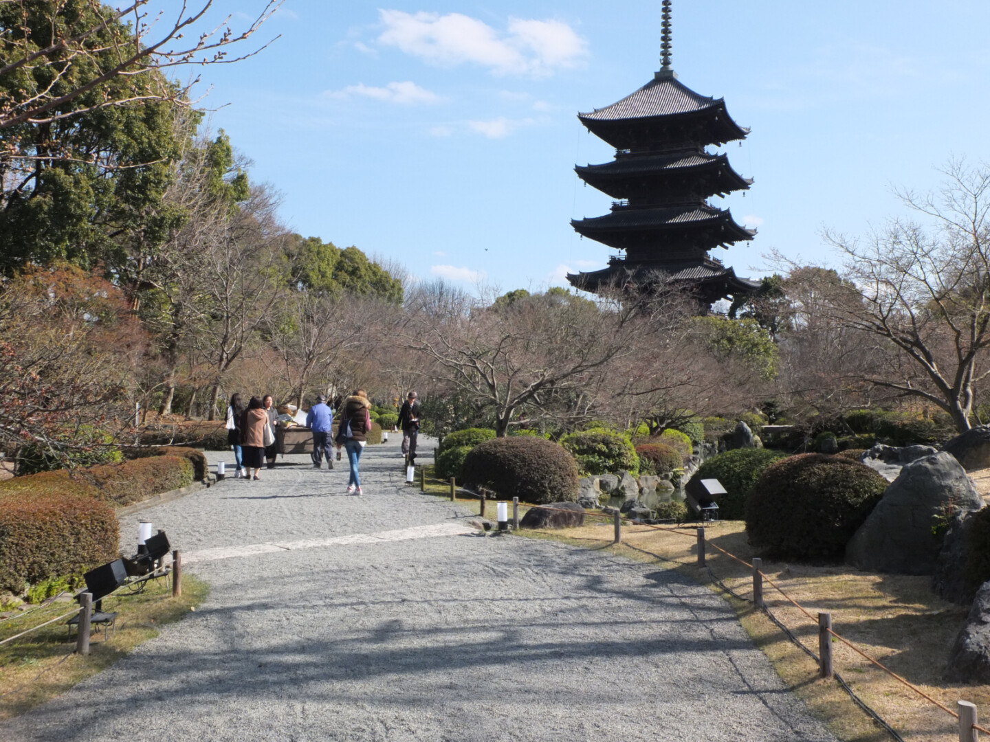 a group of people walking on a path with a pagoda in the background