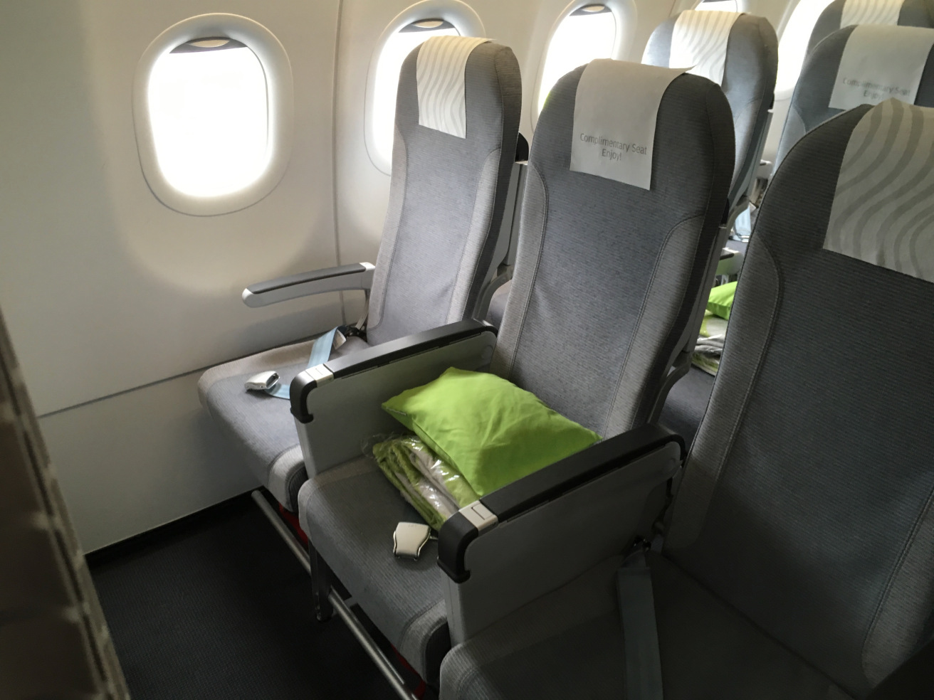 a row of grey seats with a green pillow on the side
