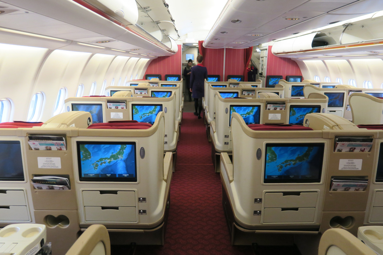 a inside of an airplane with rows of seats and monitors