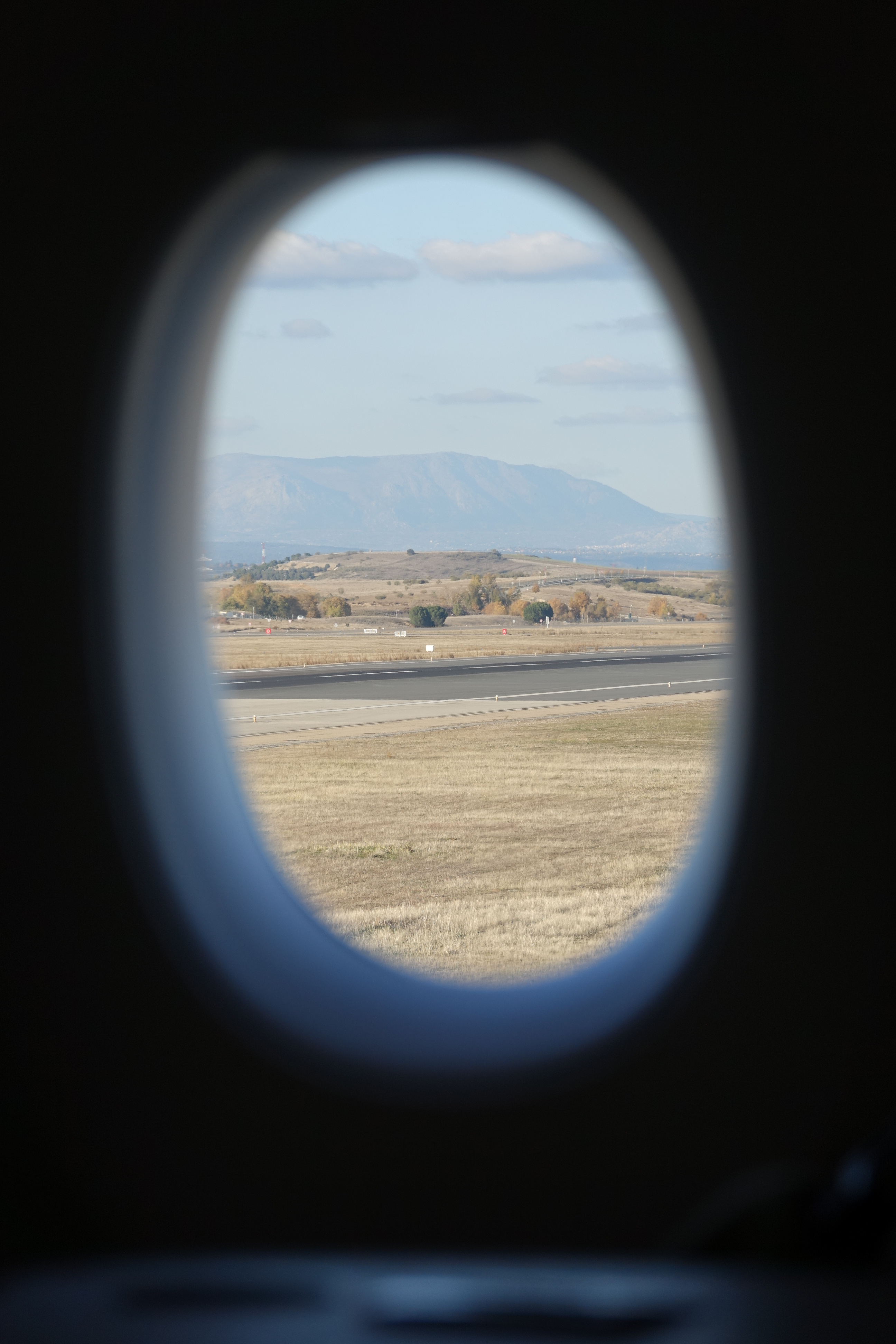 an airplane window with a view of a runway and mountains