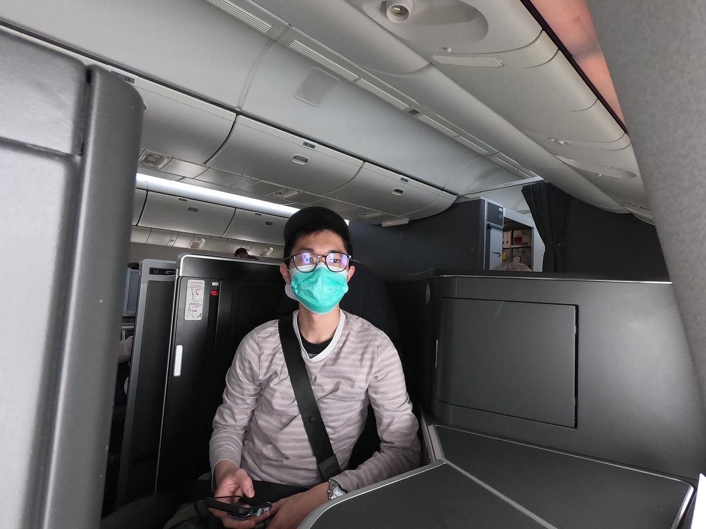 a man wearing a mask sitting in an airplane