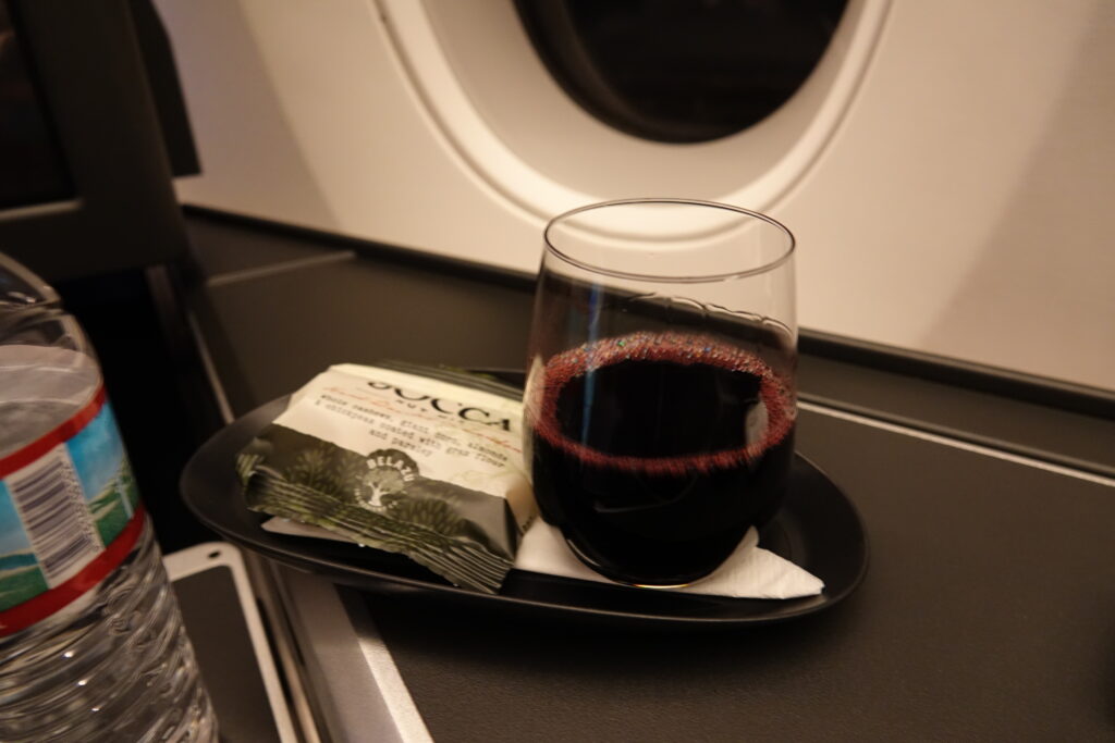 a glass of wine on a plate with a packet of food on it