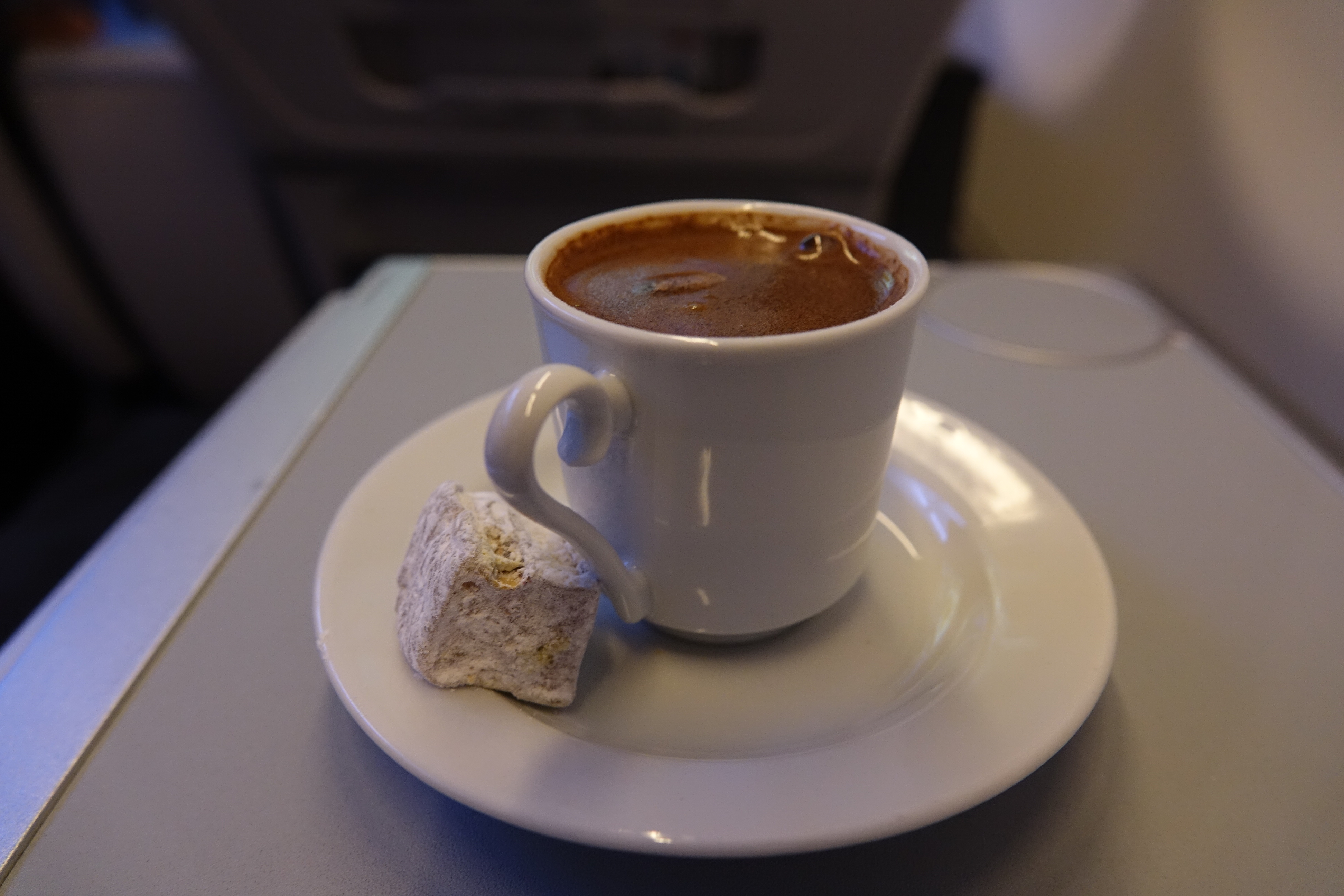 a cup of coffee and a piece of turkish delight on a plate